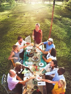 Group of friends eating dinner at a table outside in the summer