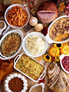 Thanksgiving table with roasted turkey, sliced ham and side dishes