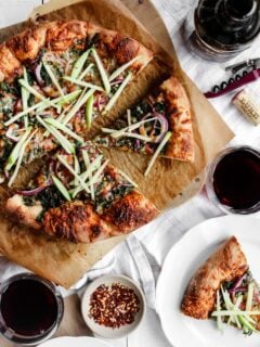 Kale pizza with BBQ sauce, matchstick apples, mozzarella, cheddar, and red onions