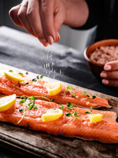 Woman seasoning salmon using a custom spice mix