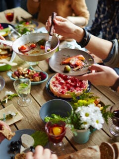 People sitting at wood dining table and eating Thanksgiving dishes together