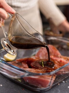 Woman pours soy sauce based marinade into glass cooking dish