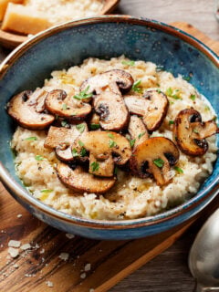 Risotto with brown champignon mushrooms on wooden background.