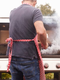 A man wearing an apron and grilling