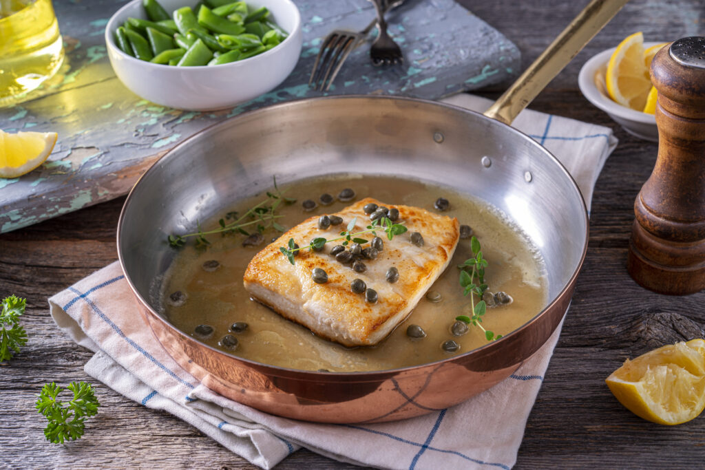 Delicious pan seared halibut with lemon brown butter and capers in a copper pan