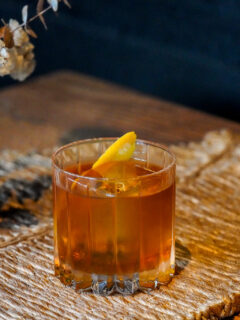 The Campfire Old Fashioned cocktail with an orange peel garnish sitting on a fall tablescape
