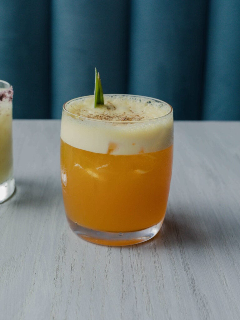The "All Bark, No Bite" pineapple mocktail in a glass with a pineapple garnish on a table.