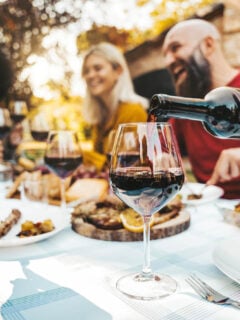 Friends enjoying red wine outside at a meal in the fall.