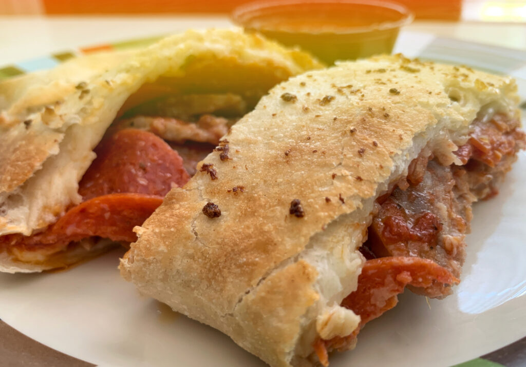 An overstuffed Stromboli, filled with meats and cheeses.