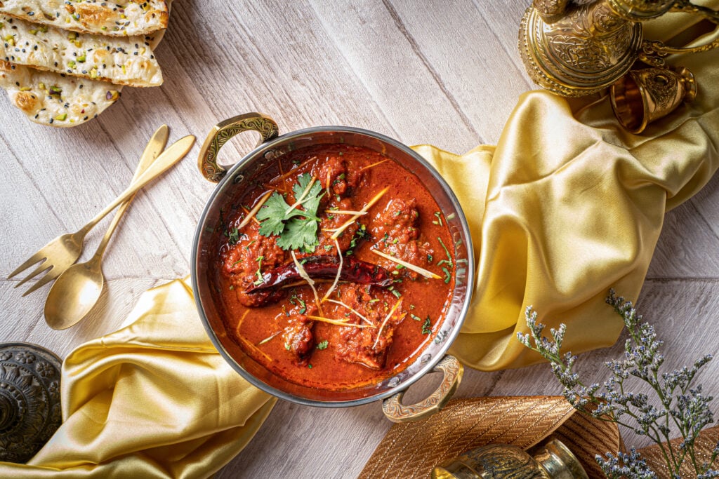 Indian spices Jodhpuri Laal Gosht or beef karahi with roti and kulcha served in a copper dish