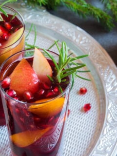 Fall and winter sangria with oranges, apples, pomegranate seeds, rosemary and spices - homemade festive drink for Thanksgiving