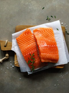 Salmon. Fresh raw salmon fish fillet with cooking ingredients, herbs and lemon on dark background, top view