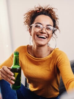Young woman smiling and drinking a nonalcoholic beer in a green glass bottle
