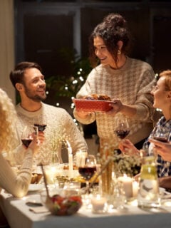 holidays, celebration and people concept - happy smiling friends having christmas dinner at home in evening