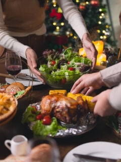 Family setting the table for Thanksgiving dinner with pie, turkey, salad, and more.