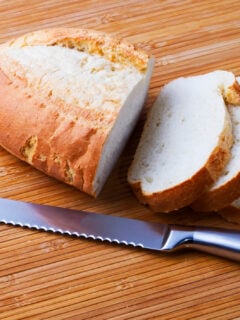 Loaf of bread cut with a serrated knife on a wooden cutting board