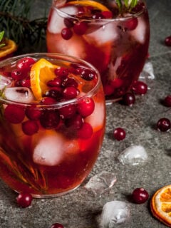 Winter drinks, cold cocktail with cranberries, orange, rosemary, with spices (cinnamon, anise) and ice