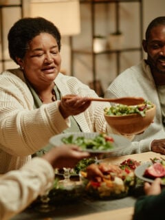 Portrait of smiling grandmother serving food while celebrating Thanksgiving with big happy family at dinner table