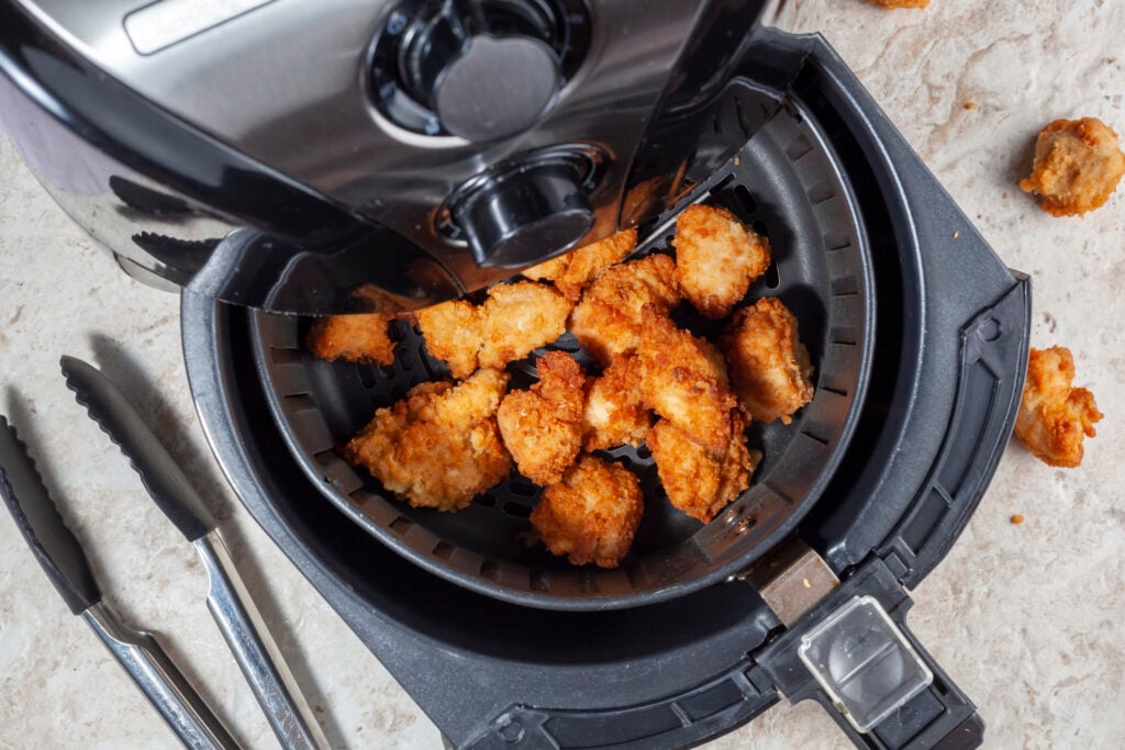 Close up flat lay image of an air fryer oven on kitchen countertop. This offers fast and easy crispy food with little or no fat by circulating hot air inside the basket.