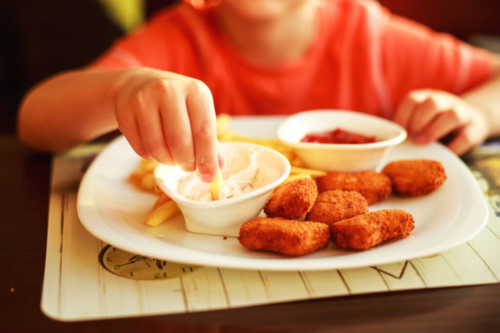 child eating french fries with chicken nuggets