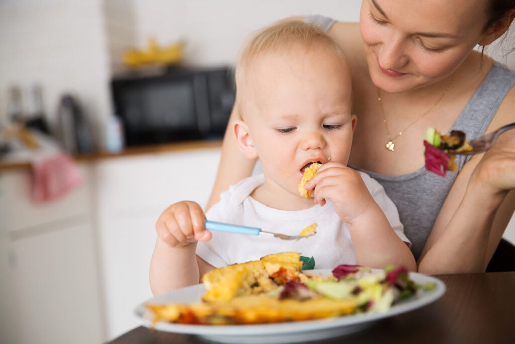Mother with her child eating together and have a fun