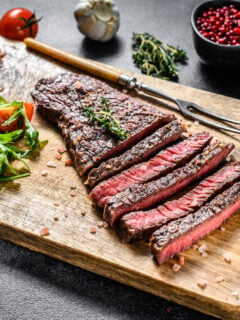 sliced steak on a cutting board. Black background. Top view.