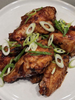 Texas Pete® Spicy Cranberry Wings on a white plate and topped with green onions.