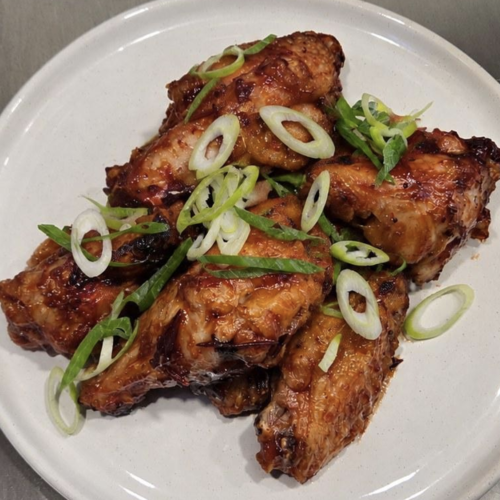 Texas Pete® Spicy Cranberry Wings on a white plate and topped with green onions.